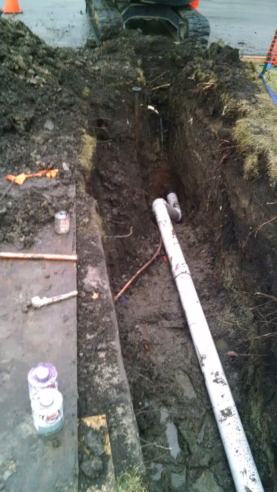 Plumber running pipe in a trench