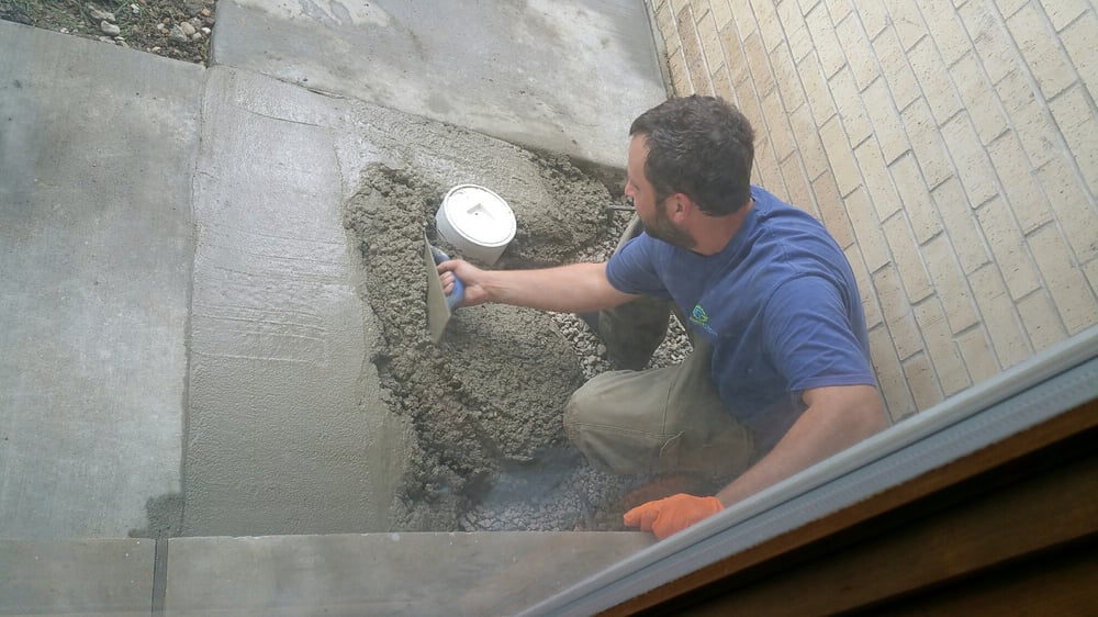Plumber laying cement around a clean out