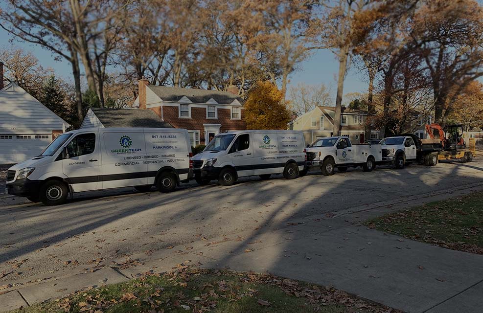 Green Tech Plumbing Vans parked in a line